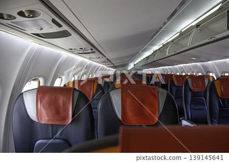 Empty cabin of the plane. Soft seats for passengers, portholes. Inside a passenger plane. A seat on the plane. Empty cabin of the plane. Soft seats for passengers, portholes. Inside a passenger plane. A seat on the plane. 139145641