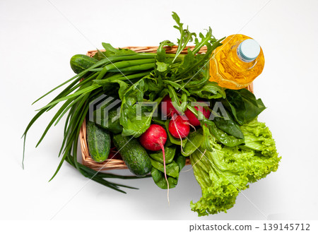 Delivery of products. Box with vegetables and sunflower oil. A set of greens for salad. Chives, lettuce, cucumbers, radishes, spinach, arugula. Isolated on a white background with place for text. Delivery of products. Box with vegetables and sunflower oil. A set of greens for salad. Chives, lettuce, cucumbers, radishes, spinach, arugula. Isolated on a white background with place for text. 139145712