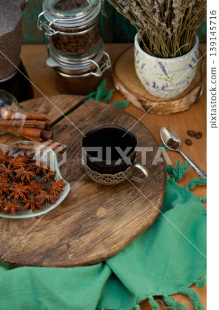 Top View of Black Coffee in Vintage Cup with Cinnamon Sticks, Star Anise and Lavender on Wood Board Top View of Black Coffee in Vintage Cup with Cinnamon Sticks, Star Anise and Lavender on Wood Board 139145716
