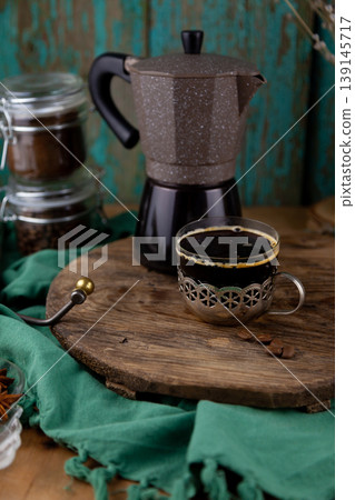 Brewed Espresso in Vintage Glass Cup with Geyser Coffee Maker on Rustic Wooden Board Background. Drink in old metal cup holder Brewed Espresso in Vintage Glass Cup with Geyser Coffee Maker on Rustic Wooden Board Background. Drink in old metal cup holder 139145717