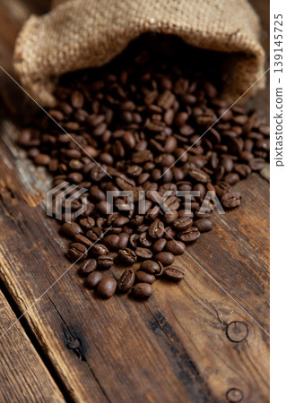 Bag of coffee on a wooden table. Coffee beans are poured. Top view, place for text. Coffee background. Food and drink. Bag of coffee on a wooden table. Coffee beans are poured. Top view, place for text. Coffee background. Food and drink. 139145725