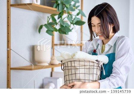一位女士過著簡單的生活,臉上帶著微笑,提著洗衣籃。 一位女士過著簡單的生活,臉上帶著微笑,提著洗衣籃。 139145739