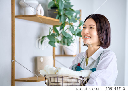 A woman, holding a clean towel, smiles and looks towards the future. A woman, holding a clean towel, smiles and looks towards the future. 139145740