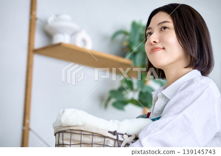A young woman, holding her laundry, gazes into the future. A young woman, holding her laundry, gazes into the future. 139145743
