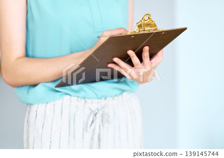 一位女士正在對著寫字板寫字。 一位女士正在對著寫字板寫字。 139145744