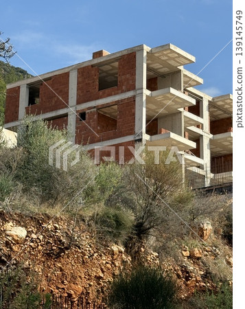Abandoned unfinished building with open windows and exposed concrete structure in rural landscape Abandoned unfinished building with open windows and exposed concrete structure in rural landscape 139145749