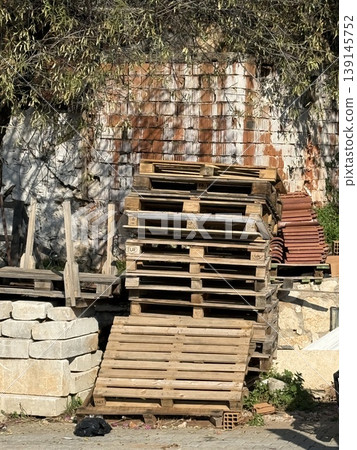 Stack of wooden pallets and bricks near textured wall outdoors, suitable for industrial background Stack of wooden pallets and bricks near textured wall outdoors, suitable for industrial background 139145752