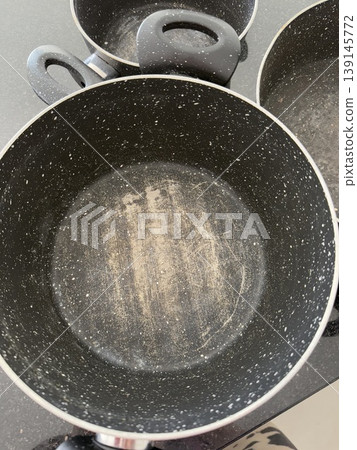 Empty cooking pot with nonstick interior and wear marks on black countertop background 139145772