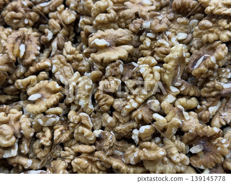 Walnut halves create a textured background featuring natural patterns and brown hues 139145778