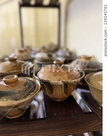 Ceramic bowls with lids on wooden shelf in pottery studio setting Ceramic bowls with lids on wooden shelf in pottery studio setting 139145781