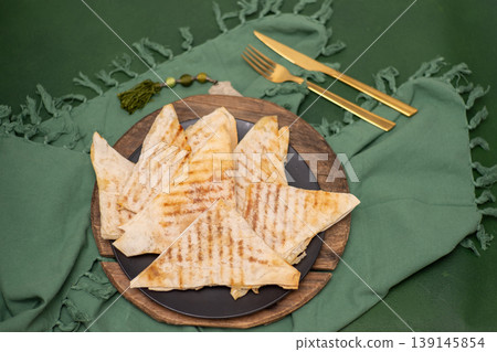 Saudi Arabia food Mutabbaq thin triangular envelopes of dough with filling fried in a pan. Flatbread is a traditional Arabic food. Saudi Arabia food Mutabbaq thin triangular envelopes of dough with filling fried in a pan. Flatbread is a traditional Arabic food. 139145854
