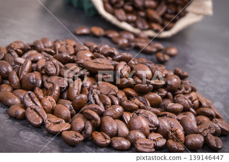 Heap of dark roasted coffee grains in jute bag Heap of dark roasted coffee grains in jute bag 139146447