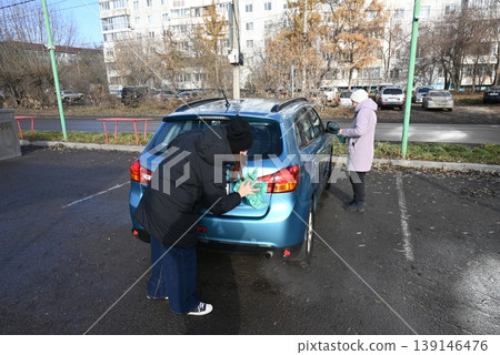 Person cleaning car windows in a parking lot during winter morning Person cleaning car windows in a parking lot during winter morning 139146476