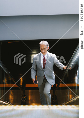 Senior man riding escalator Senior man riding escalator 139146846