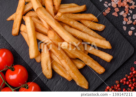 French fries, a salty, crispy, homemade snack with spices. French fries on a black background 139147211