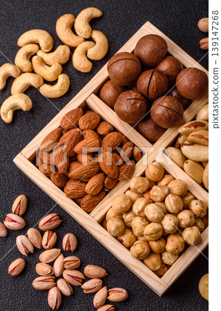 Wooden box with macadamia nuts, almonds, pistachios, and hazelnuts. Nuts as a food background Wooden box with macadamia nuts, almonds, pistachios, and hazelnuts. Nuts as a food background 139147268