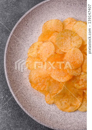 Crispy potato chips, golden slices seasoned with salt and spices. Potato chips Crispy potato chips, golden slices seasoned with salt and spices. Potato chips 139147407