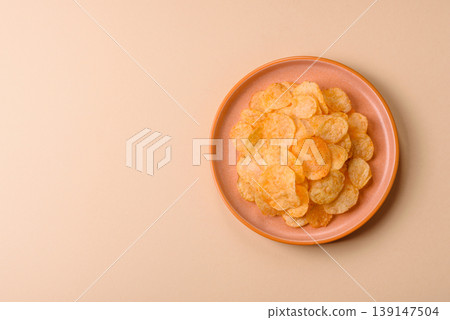 Crispy potato chips, golden slices seasoned with salt and spices. Potato chips Crispy potato chips, golden slices seasoned with salt and spices. Potato chips 139147504