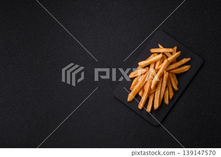 French fries, a salty, crispy, homemade snack with spices. French fries on a black background 139147570