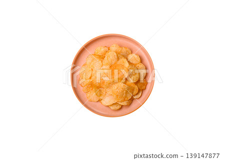 Crispy potato chips, golden slices seasoned with salt and spices. Potato chips Crispy potato chips, golden slices seasoned with salt and spices. Potato chips 139147877