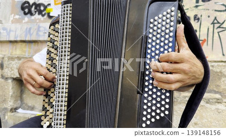 Male hands of musician playing the accordion at urban street. The detailed view highlights texture of instrument, capturing rhythm, tradition, and the expressive character of live music performance Male hands of musician playing the accordion at urban street. The detailed view highlights texture of instrument, capturing rhythm, tradition, and the expressive character of live music performance 139148156