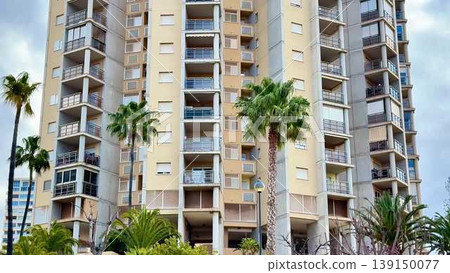 Video shows a tall apartment building with palm trees and life 139150077