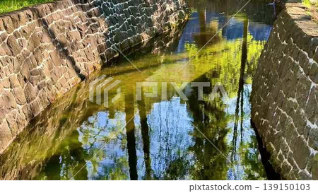 A serene park video shows a stone wall by a stream, enhancing nature A serene park video shows a stone wall by a stream, enhancing nature 139150103