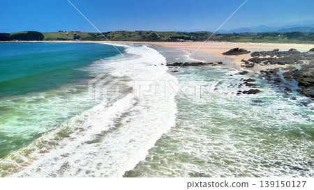 Stunning and breathtaking Aerial View of a Serene Beach featuring Waves and a Rocky Shoreline Stunning and breathtaking Aerial View of a Serene Beach featuring Waves and a Rocky Shoreline 139150127