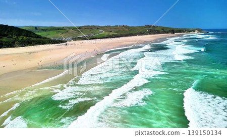 A beautiful beach with stunning waves and surfers enjoying a sunny day by the ocean A beautiful beach with stunning waves and surfers enjoying a sunny day by the ocean 139150134