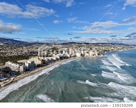 Bustling coast with shimmering waves, Lively oceanfront scene with energetic waves and sunny structures Bustling coast with shimmering waves, Lively oceanfront scene with energetic waves and sunny structures 139150209