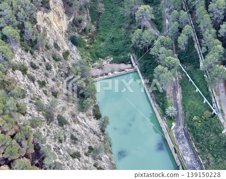 Cliffside water collection system adjacent to vibrant turquoise reservoir and utility inspection route Cliffside water collection system adjacent to vibrant turquoise reservoir and utility inspection route 139150228