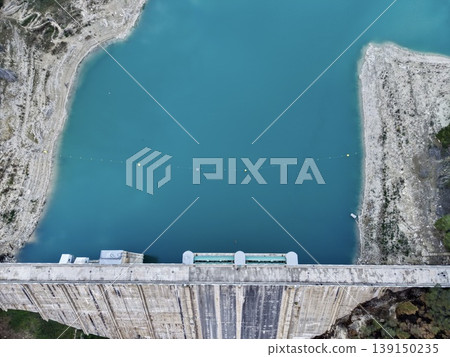 Dam reservoir reflecting tranquil waters, Calm surface of water behind dam with vibrant turquoise pools Dam reservoir reflecting tranquil waters, Calm surface of water behind dam with vibrant turquoise pools 139150235