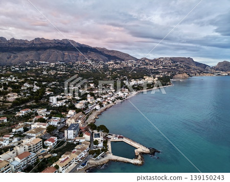 Evening hues brighten peaceful coastal settlements, Sunset hues fill calm seaside towns and rolling hills 139150243