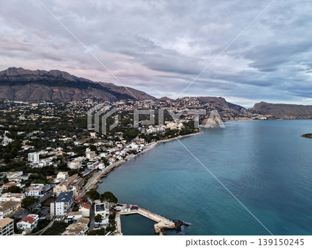 Elevated image capturing serene neighborhood with turquoise waters and mountain scenery under cloudy sky Elevated image capturing serene neighborhood with turquoise waters and mountain scenery under cloudy sky 139150245