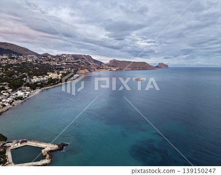 Lonely shoreline featuring cliffs and small town, Secluded seaside scene with island and overcast sky Lonely shoreline featuring cliffs and small town, Secluded seaside scene with island and overcast sky 139150247