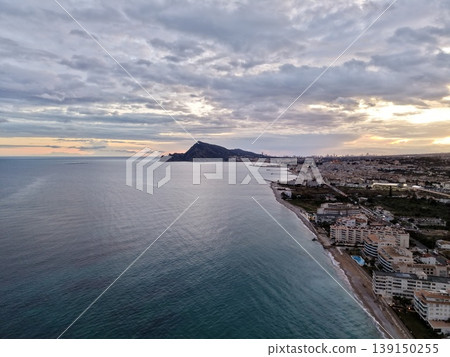 Seaside town with glowing lights, Sunlit shoreline featuring urban development and tranquil beaches Seaside town with glowing lights, Sunlit shoreline featuring urban development and tranquil beaches 139150255