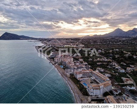 Evening seaside ambiance, Sunset sky with glowing lights, Twilight over coast with vibrant cloud display Evening seaside ambiance, Sunset sky with glowing lights, Twilight over coast with vibrant cloud display 139150259
