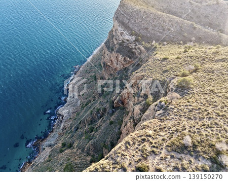 Quiet shore with textured rocks, Peaceful seaside with craggy cliffs and soothing ocean waves Quiet shore with textured rocks, Peaceful seaside with craggy cliffs and soothing ocean waves 139150270