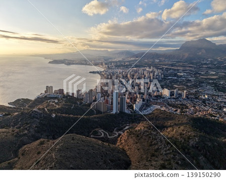 Urban sunset view, Metropolitan horizon illuminated with shimmering lights and scenic mountains 139150290