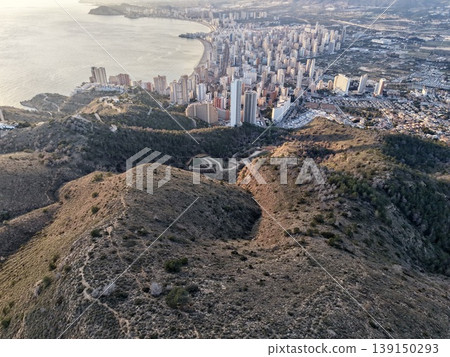 Calm pathway through rugged landscape, Tranquil road meandering over stony grounds towards city views Calm pathway through rugged landscape, Tranquil road meandering over stony grounds towards city views 139150293