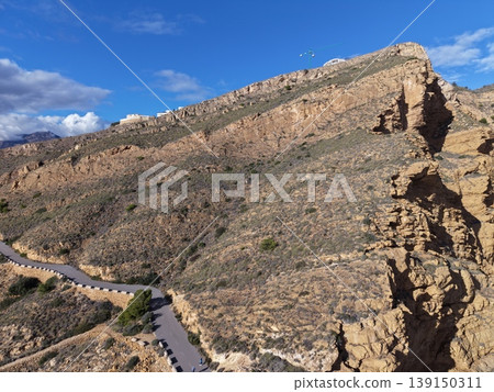 Bold sandstone cliff against sky, Imposing geological structure with detailed shadows and vibrant sky 139150311