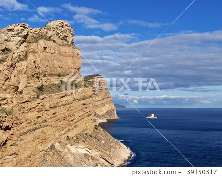 Majestic cliff with lone vessel, Expansive ocean scene with distant boat and layered cliffs Majestic cliff with lone vessel, Expansive ocean scene with distant boat and layered cliffs 139150317