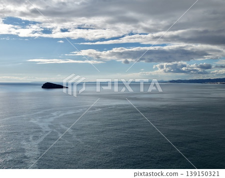 Isolated island scene, Remote and rugged island surrounded by peaceful water and distant shoreline views Isolated island scene, Remote and rugged island surrounded by peaceful water and distant shoreline views 139150321
