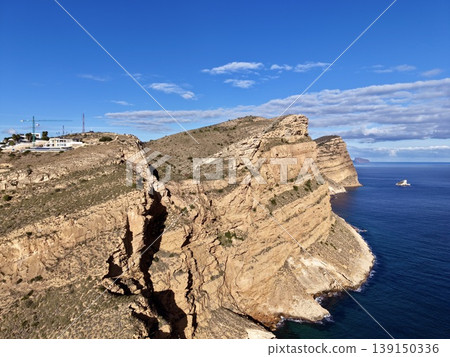 Sunshine highlights cliff and sea, Radiant cliffs ascend over tranquil blue waters with distant boat Sunshine highlights cliff and sea, Radiant cliffs ascend over tranquil blue waters with distant boat 139150336