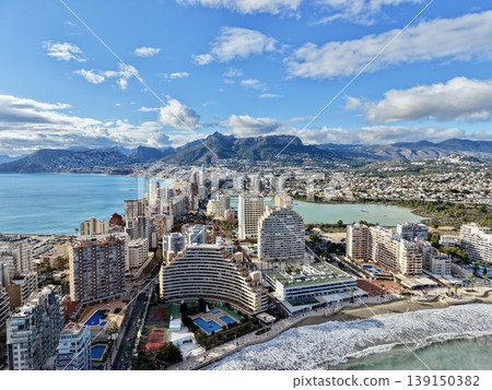 Expansive shoreline scene illustrating rolling surf alongside city development and hotel supervision Expansive shoreline scene illustrating rolling surf alongside city development and hotel supervision 139150382
