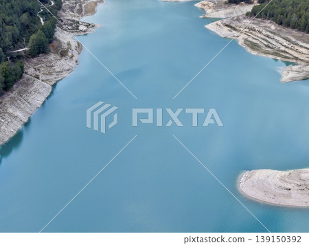 Expansive lake with distant mountains, Panoramic view of calm turquoise lake and surrounding peaks Expansive lake with distant mountains, Panoramic view of calm turquoise lake and surrounding peaks 139150392