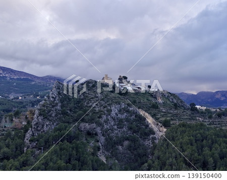Historic white chapel on hillside, Old chapel situated amidst dense pine forest with mountain scenery Historic white chapel on hillside, Old chapel situated amidst dense pine forest with mountain scenery 139150400