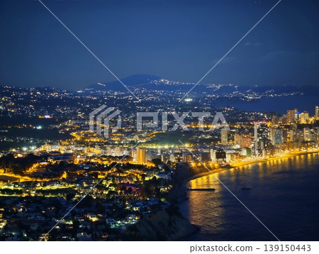 Lively seaside metropolis illuminated after dark. City by water glows with lively lights and energy Lively seaside metropolis illuminated after dark. City by water glows with lively lights and energy 139150443