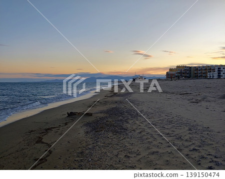 Coastal apartments by waves. Sunset at coastal retreat with highrise apartments and soothing ocean waves 139150474