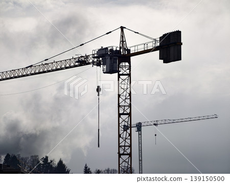 Gloomy metropolitan skyline shaded by clouds with cranes and steel frameworks illustrating development Gloomy metropolitan skyline shaded by clouds with cranes and steel frameworks illustrating development 139150500